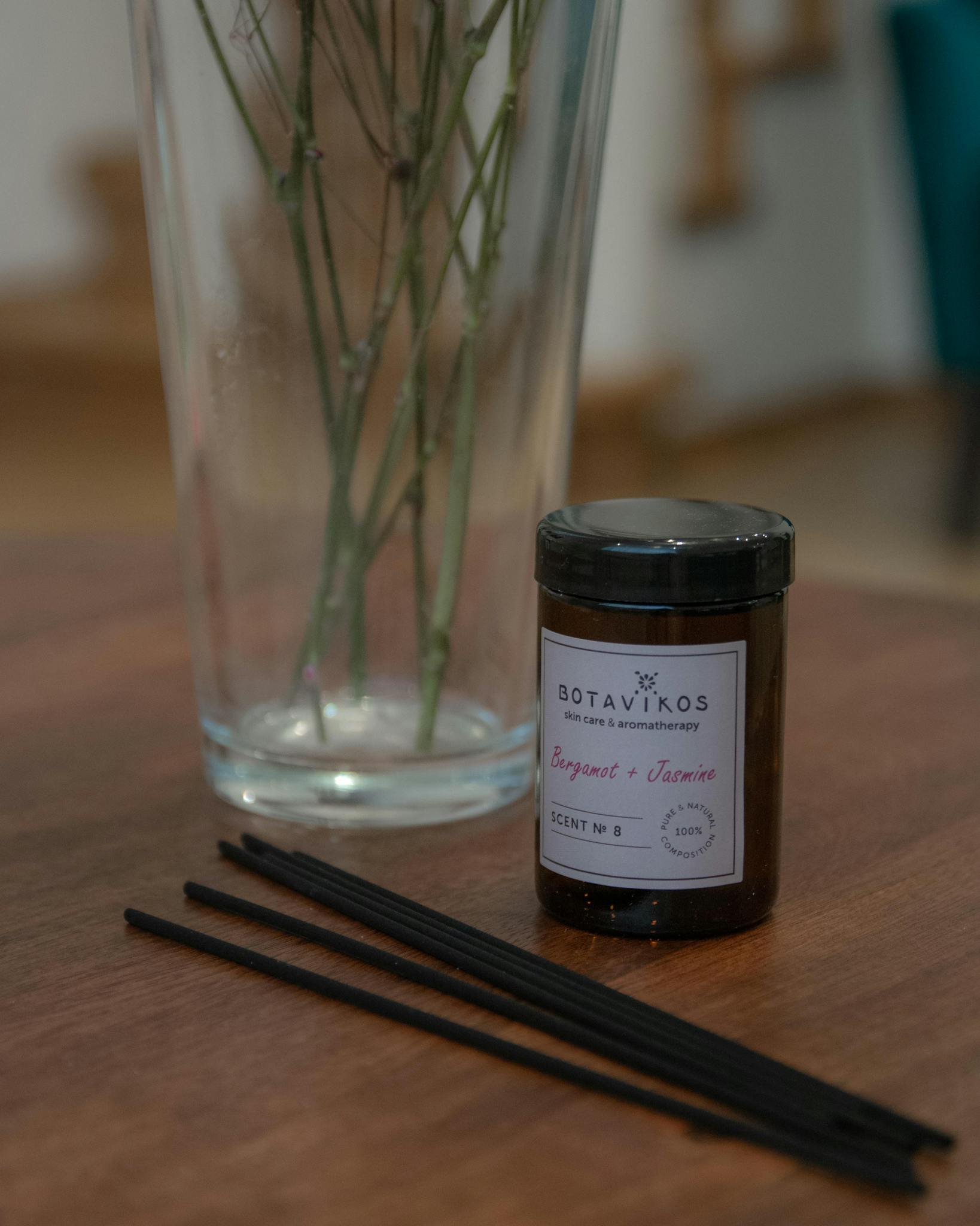 Close-up of aromatherapy setup with incense and vase on wooden table.