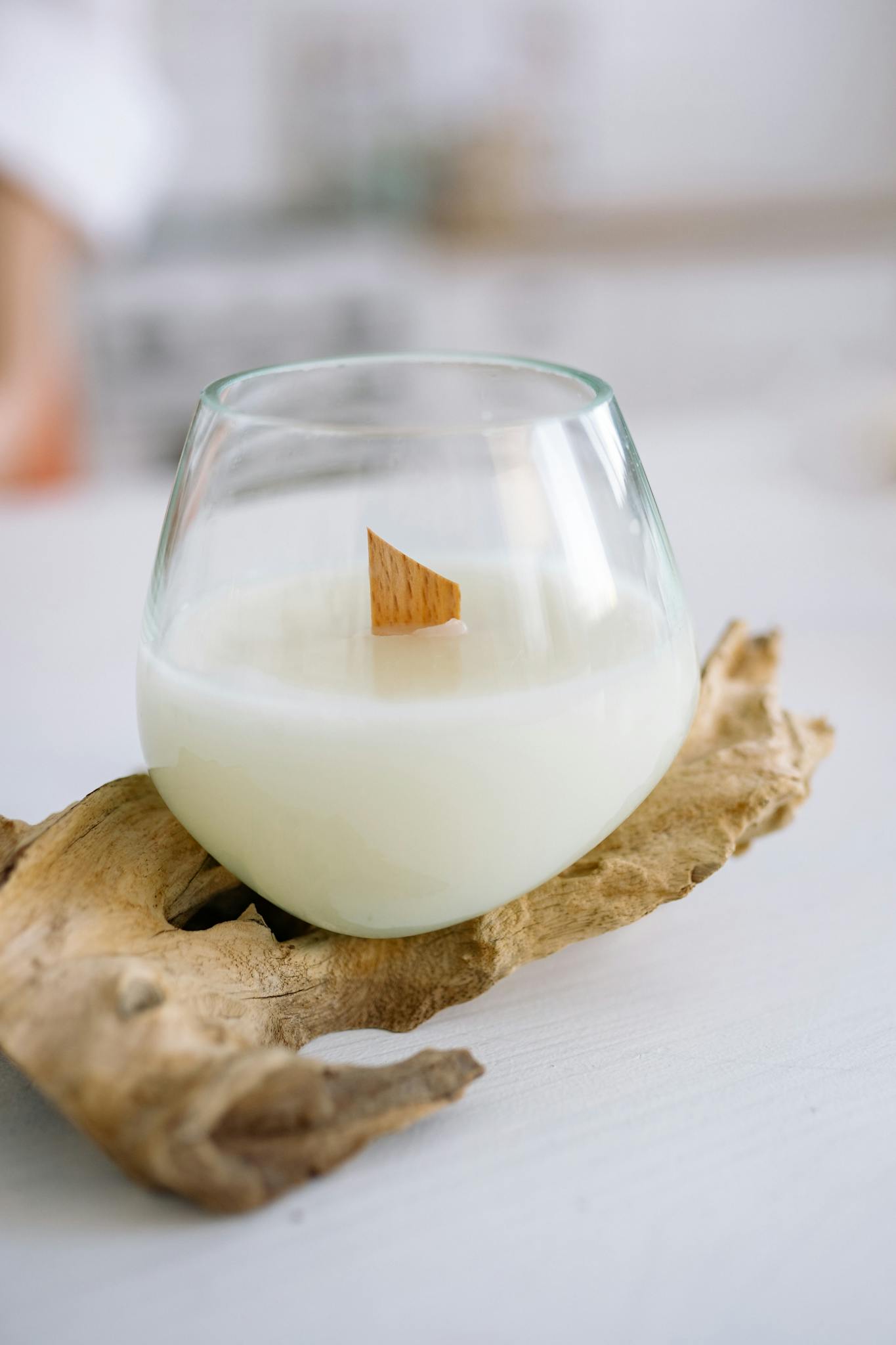 Minimalist candle placed in a clear glass on driftwood, creating a calming atmosphere.
